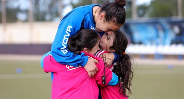 Fun Coaching! Two young girls happily cling to their female football coach during the “Live Your Goals Festival”   Copyright © Domenic Aquilina