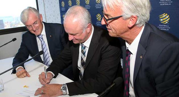 Football Federation Australia Chairman Steven Lowy, left, and Chief Executive David Gallop, right, watch as Graham Arnold signs a four-year contract to coach the Australian national soccer team in Sydney, Thursday, March 8, 2018. Arnold, current coach of A-League champions Sydney FC, will replace Dutchman Bert van Marwijk after the World Cup in Russia. (AP Photo/Rick Rycroft)