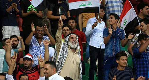 In this Sept. 9, 2017 file photo, soccer fans wave national flags during a friendly match, in Basra, Iraq. An Iraq-Qatar match, part of a friendly soccer tournament this week with Syria and Qatar, is to start Wednesday, March 21, 2018, in Basra. While friendly matches have been allowed for some time, last week FIFA lifted a three-decade ban on international competitions for the Iraqi cities of Basra, Karbala and Irbil, considered to be the safest in Iraq -- but not Baghdad, which still sees militant attacks. (AP Photo/Nabil al-Jourani, File)