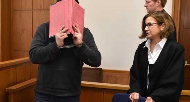 Former nurse, only identified as Niels H. hides his face behind a folder when arriving in the courtroom besides his lawyer Ulrike Baumann, right, in Oldenburg, Germany