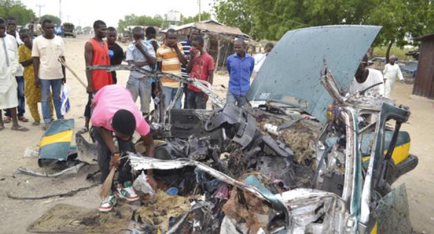 In this Oct. 12, 2016, file photo, people gathered at the scene of a suicide car bombed explosion in Maiduguri, Nigeria. Radical Islamic militants from Boko Haram are increasingly forcing children to carry out bombings, with the number of attacks since January already nearly reaching the total for all of last year, according to a report released Wednesday, April 12, 2017 by the U.N. children's agency. (AP Photo/Jossy Ola, File)