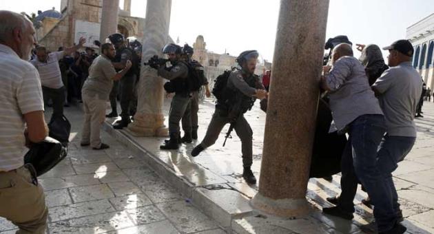 An Israeli police officer aims his weapon at Palestinians during clashes at the Al Aqsa Mosque compound in Jerusalem's Old City, Thursday, July 27, 2017.