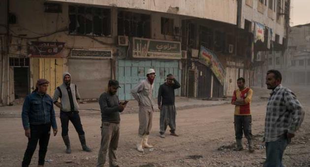 In this Nov. 15, 2017 photo, construction workers gather on a commercial street in the Old City of Mosul, Iraq.