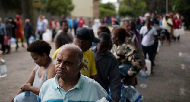 Residents queue to fill containers with water from a source of natural spring water in Cape Town, South Africa, Friday, Feb. 2, 2018. South Africa's drought-hit city of Cape Town introduced new water restrictions in an attempt to avoid what it calls 