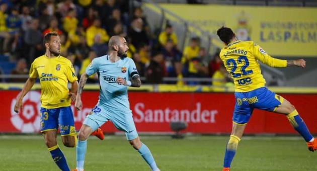 Barcelona's Aleix Vidal, center, watches as Las Palmas' Ximo Navarro, right, jumps for a high ball during a Spanish La liga soccer match at the Gran Canaria stadium in the Canary island of Las Palmas, Thursday March 1, 2018. (AP Photo/Lucas de Leon)