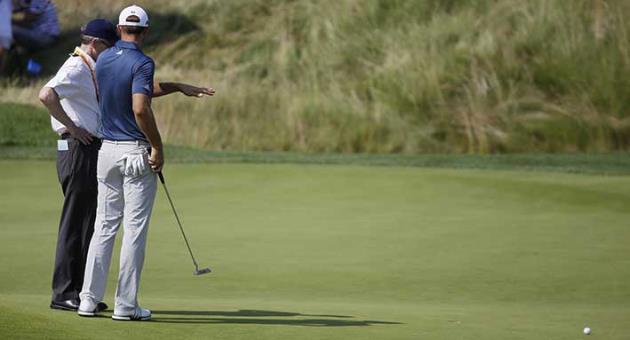 In this June 19, 2016, file photo, Dustin Johnson, right, talks to a rules official on the fifth green during the final round of the U.S. Open golf tournament at Oakmont Country Club in Oakmont, Pa. The USGA and R&A introduced a modern set of rules effective in 2017 designed to make them easier to understand. (AP Photo/John Minchillo, File)