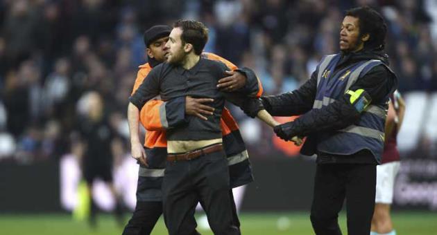 A Pitch invader is seized by security staff during the English Premier League soccer match between Burnley and West Ham at the Olympic London Stadium in London, Saturday, March 10, 2018. (Daniel Hambury/PA via AP)