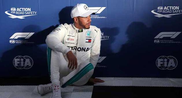 Mercedes driver Lewis Hamilton of Britain sits on the ground after qualifying at the Australian Formula One Grand Prix in Melbourne, Saturday, March 24, 2018. Hamilton has poll ahead of Ferrari driver Sebastian Vettel of Germany and Ferrari driver Kimi Raikkonen of Finland. (AP Photo/Rick Rycroft)